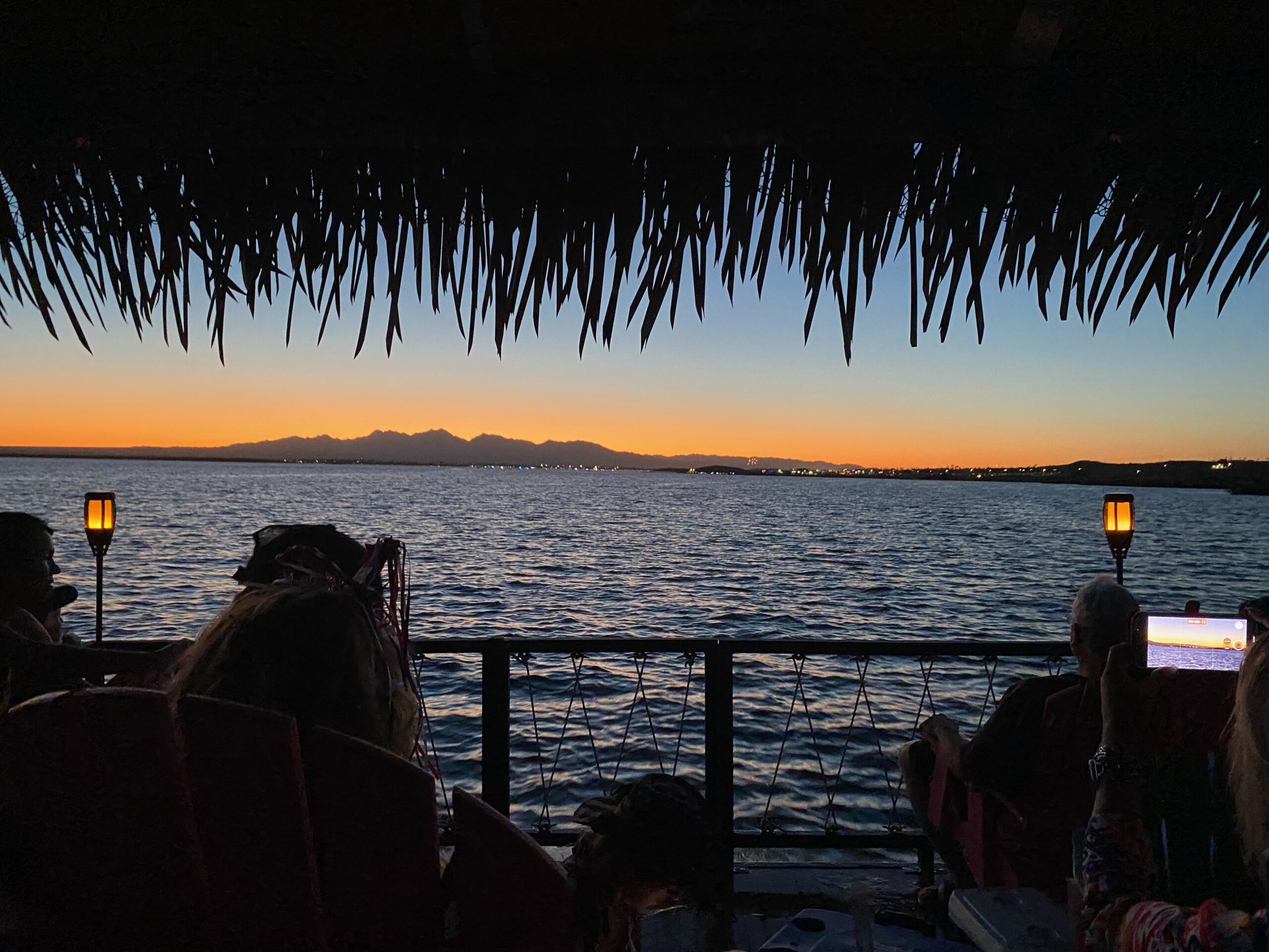 a group of people sitting on a deck overlooking a body of water