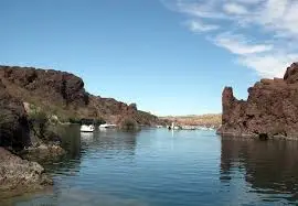 a body of water with rocks and a blue sky - Lake Havasu Boat Rentals